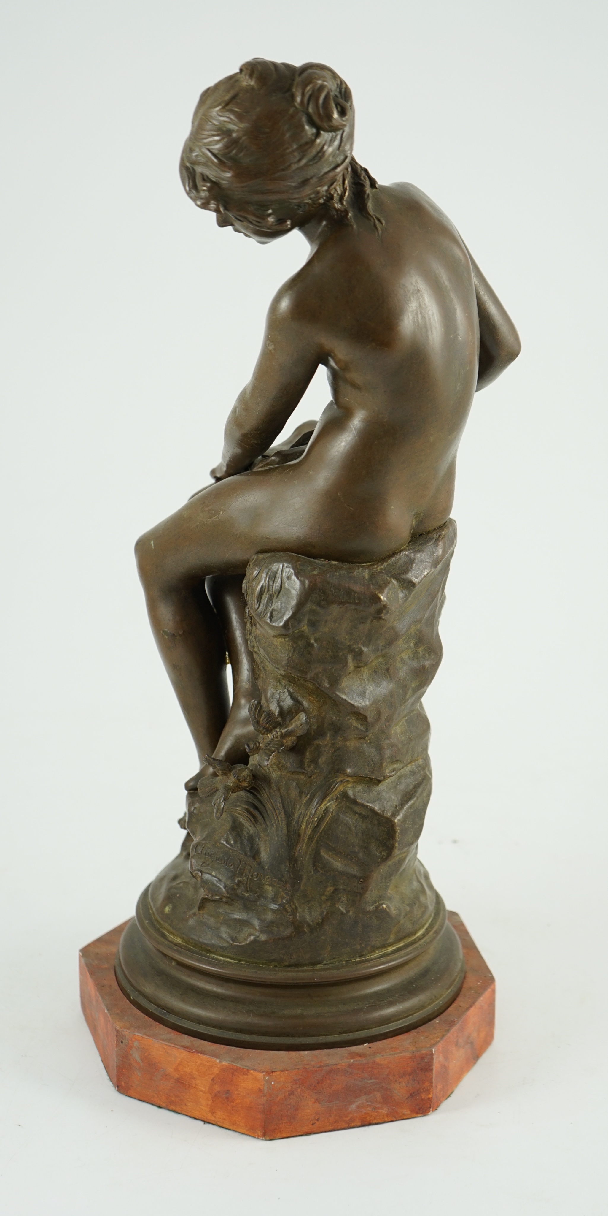 Auguste Moreau (French, 1834-1917). A bronze figure of a nude girl seated on a mound holding a book with birds at her feet, overall height 45cm